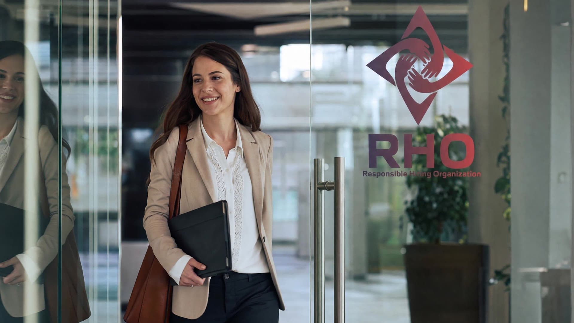 Visitor carrying a folder smiling as she walks into an office through glass doors