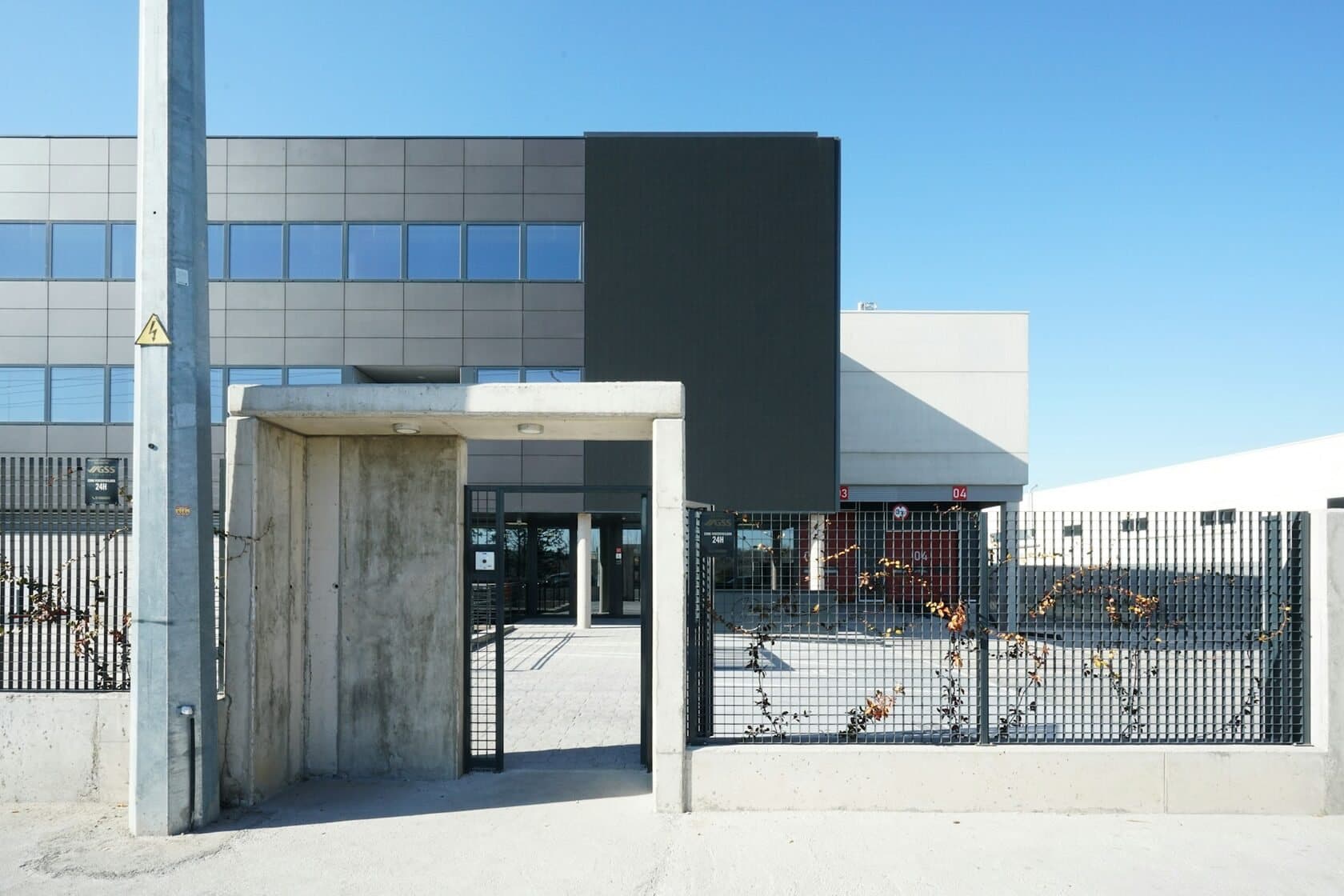 Modern industrial building behind a fence and a concrete gateway